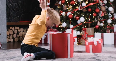 Joyful child opens large box with gift and looks into it Video stock 213971779
