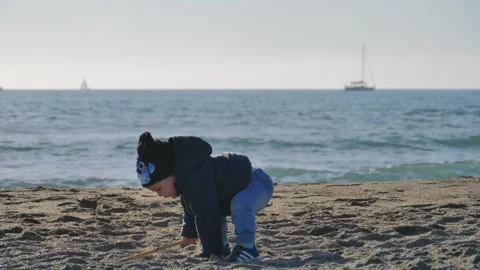 Joyful Child Playing in Soft Sand by the Ocean on a Sunny Day Stock Footage 281297855
