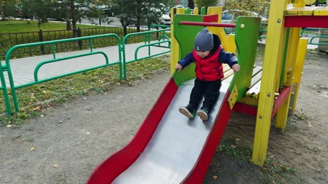 Joyful child sits on slide tapping feet. Stock Footage 255076662