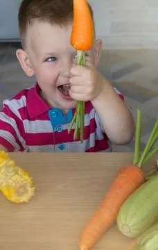 Joyful Child with Vegetables in the Kitchen Stock-Fotos