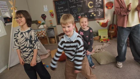 Joyful Children Enjoying Dancing with Young Teacher in Kindergarten Classroom Stock Footage 332326962
