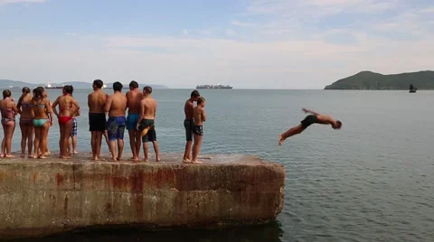 Joyful children jumping and diving into the sea from the old dock Stock Footage 53312692