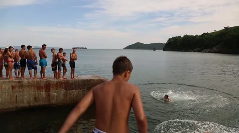 Joyful children jumping and diving into the sea from the old dock Stock Footage 53312841