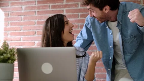 Joyful couple feeling ecstatic while looking at a laptop computer, celebrating Stock Footage 334105736