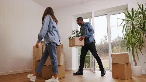A joyful couple moves boxes into their new home, setting them down in an empty Stock Footage 283983630