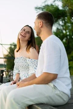 Joyful couple sharing laughter at sunset on a wooden dock Stock Photos