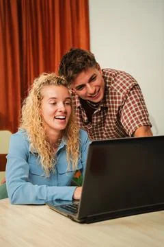 Joyful couple sharing laughter while browsing on a laptop, enjoying a delightful Stock Photos