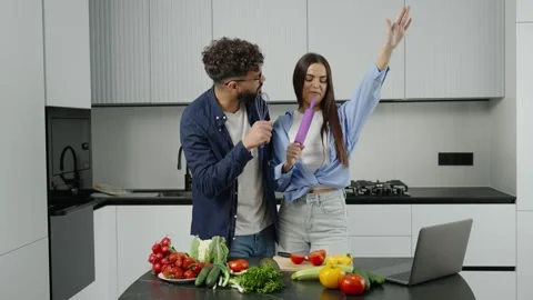 Joyful couple singing and dancing in the kitchen while cooking Stock Footage 335333899