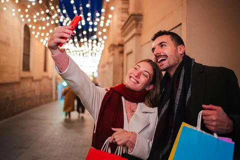 Joyful Couple Taking Selfie While Shopping Together During Festive Evening With Stock Photos
