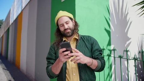 Joyful cute guy standing on corner with phone staying up to date in social media Stock Footage 108427943