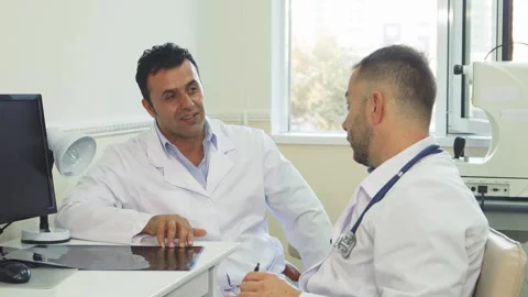 Joyful doctors share a light moment while discussing patient care Stock Footage 311986441