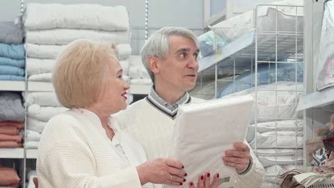 Joyful elderly couple sharing laughter while shopping for cozy home goods Stock Footage 311179800