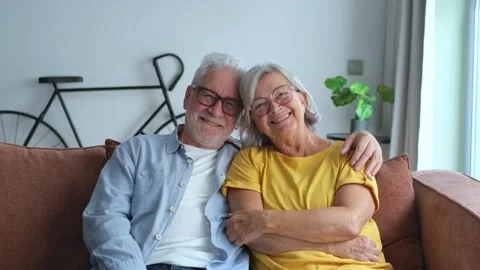 Joyful Elderly Couple Sits Lovingly on a Couch, Sh Stockbeeldmateriaal 333200909
