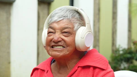 Joyful elderly woman enjoying music with wireless headphones. Stock Footage 283671453