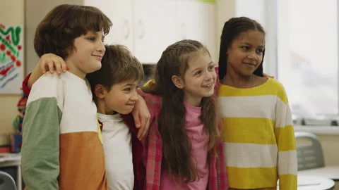 Joyful elementary school pupils hugging and smiling in classroom together Stock Footage 335682107
