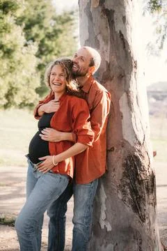 Joyful Expectant Couple Embracing by a Tree Stock Photos