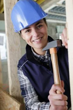 Joyful experienced builder smiling while hammering a nail Stock Photos