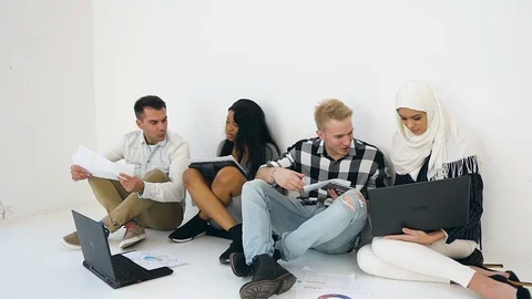 Joyful experienced young multiethnic men and women sitting on the office floor Stock Footage 121843288