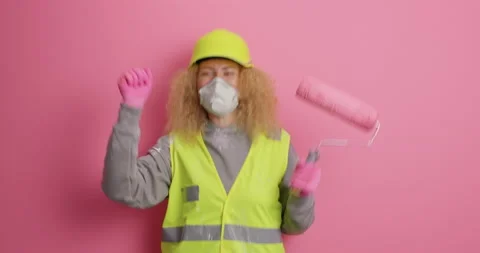 Joyful female construction worker dances happily with paint roller jumps and Stock Footage 155862244