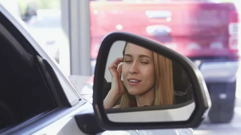 Joyful female driver beaming in the side mirror of her new car Stock Footage 311916166