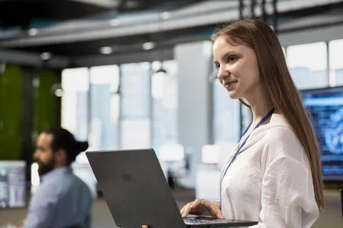Joyful female engineer adjusting deep learning algorithms parameters on laptop Foto stock