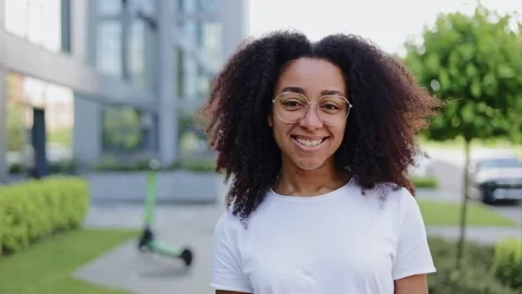Joyful female looking directly at camera with building and scooter on background Stock Footage 280373715