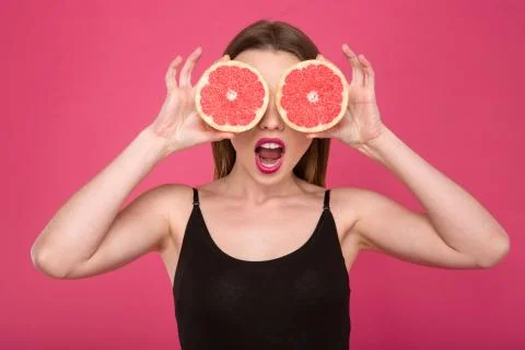 Joyful female with two half of grapefruit instead eyes Stock-Fotos