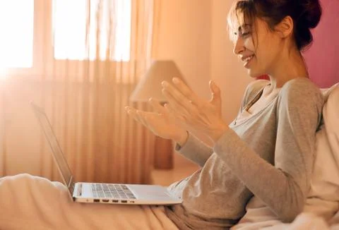 Joyful female using laptop computer and video call with friend in home, sunlight Stock Photos