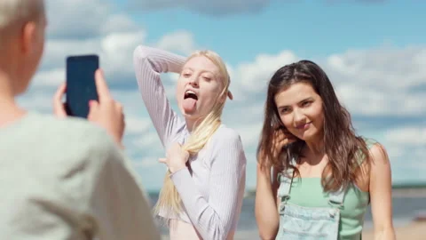 Joyful girlfriends having fun posing for short social media video on beach Stock Footage 158548911