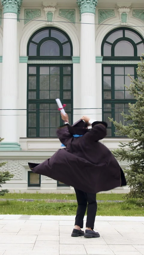 Joyful graduate guy jumps dancing in front of old building Stock Footage 313927077