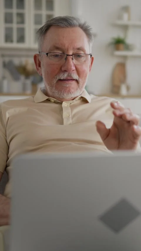 Joyful grey-haired old man playing video game on portable computer at home Video stock 287183775