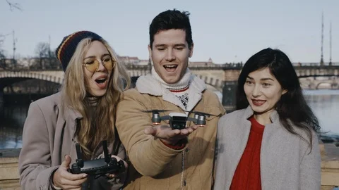 Joyful group of friends in park setting up drone. Aero shooting, lifestyle Video stock 123797982