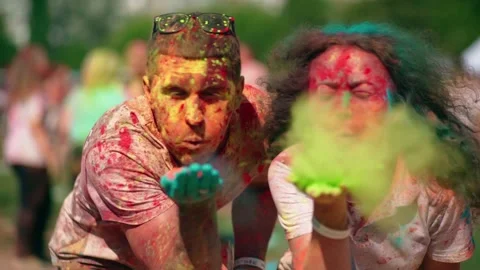 Joyful guy and girl blowing paints into the lens at the festival of colors Holi Video stock 229584853