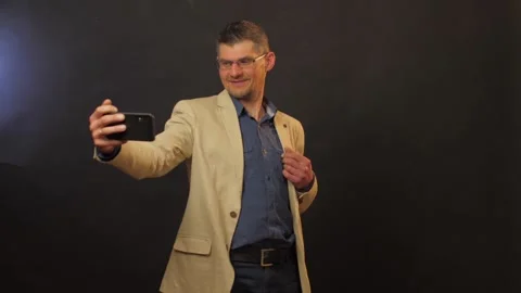 Joyful guy in glasses and jacket holds black smartphone Stock Footage 135131196