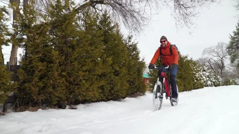 A joyful guy rides a bicycle through freshly fallen snow Stock Footage 263577036