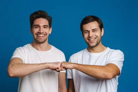 Joyful handsome friends guys smiling and fist bumping Stock Photos