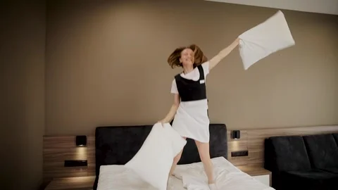 Joyful housekeeper having fun while preparing bed with pillows in cozy hotel Stock Footage 300997090