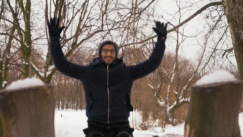 Joyful Indian Guy in Glasses Rides on a Wooden Swing in the Winter Forest Video stock 101548104