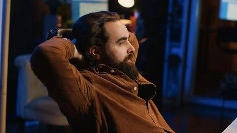 Joyful IT admin pleased after solving script errors, lounging on desk chair Stock Photos