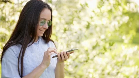 Joyful lady is typing message or dialing number and calling by mobile phone in Stock Footage 201991891