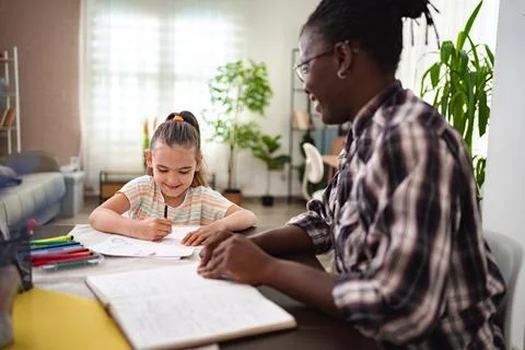 Joyful learning moment between a child and an adult at home Stock Photos