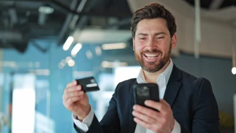 Joyful Man Completes Online Purchase Using Phone And Credit Card Video stock 329148448