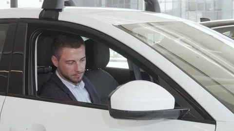 Joyful man exploring the sleek interior of a new car Stock Footage 311946010