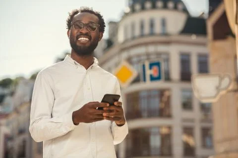 Joyful man looking up while standing with smartphone Stock Photos