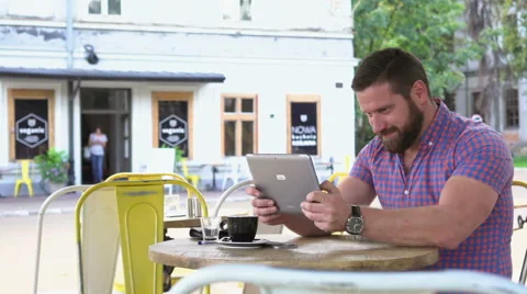 Joyful man playing game on tablet in cafe, slider shot right Vídeo Stock 67630109