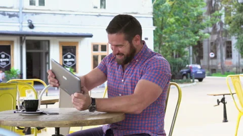 Joyful man playing game on tablet in cafe, slider shot left Vídeo Stock 67630200