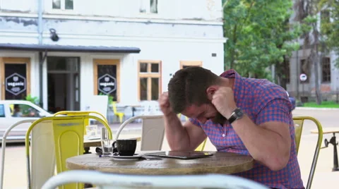 Joyful man playing game on tablet in cafe Vídeo Stock 67630259