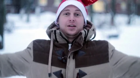Joyful man in red hat falls in the snow Stock Footage 70678827