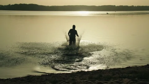 Joyful man running into a pond at sunset Vidéo 207783932