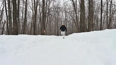 Joyful man runs through a snowy forest in a winter wonderland Stock Footage 338414213